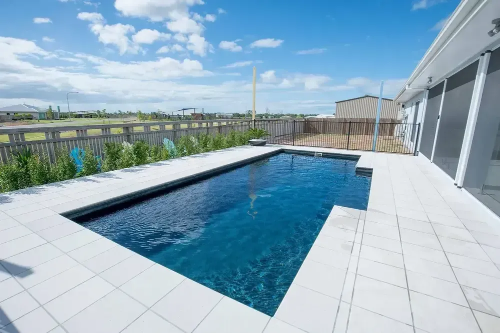 There is a Large Swimming Pool in the Backyard of a House — Sun City Pools In Hyde Park, QLD