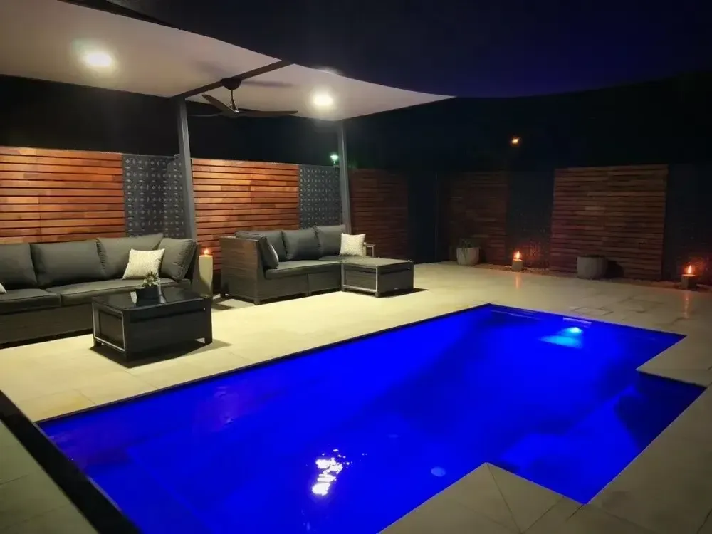 A Large Swimming Pool is Lit Up at Night — Sun City Pools In Hyde Park, QLD
