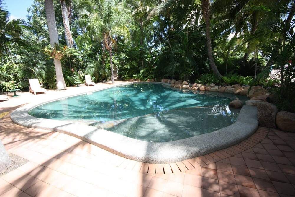 A Large Swimming Pool With Blue Tiles and Trees in the Background — Sun City Pools In Hyde Park, QLD