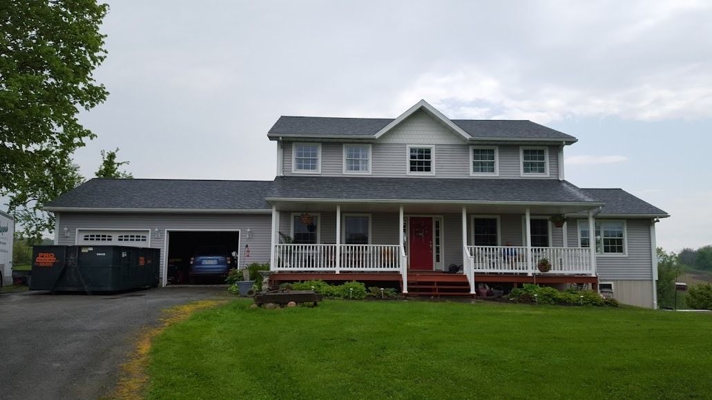 Two-story gray house with red front porch and a driveway, seen from the front lawn