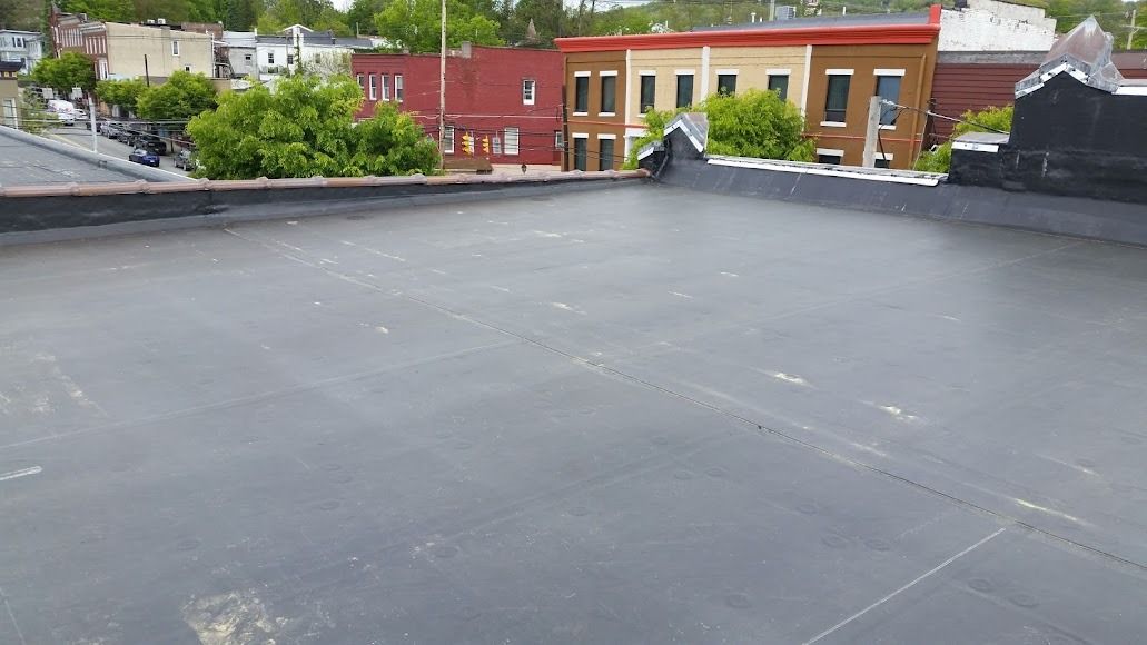 Rooftop with a flat gray surface overlooking red and yellow buildings under a cloudy sky