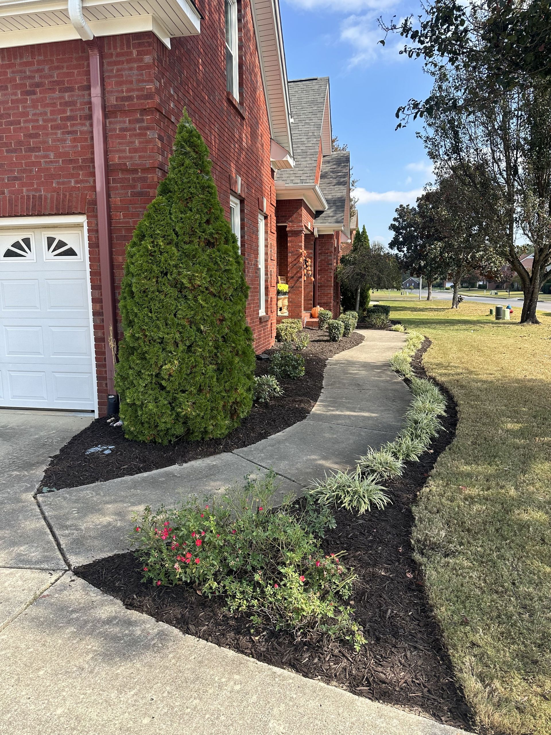 Red brick house with a walkway lined with landscaping.