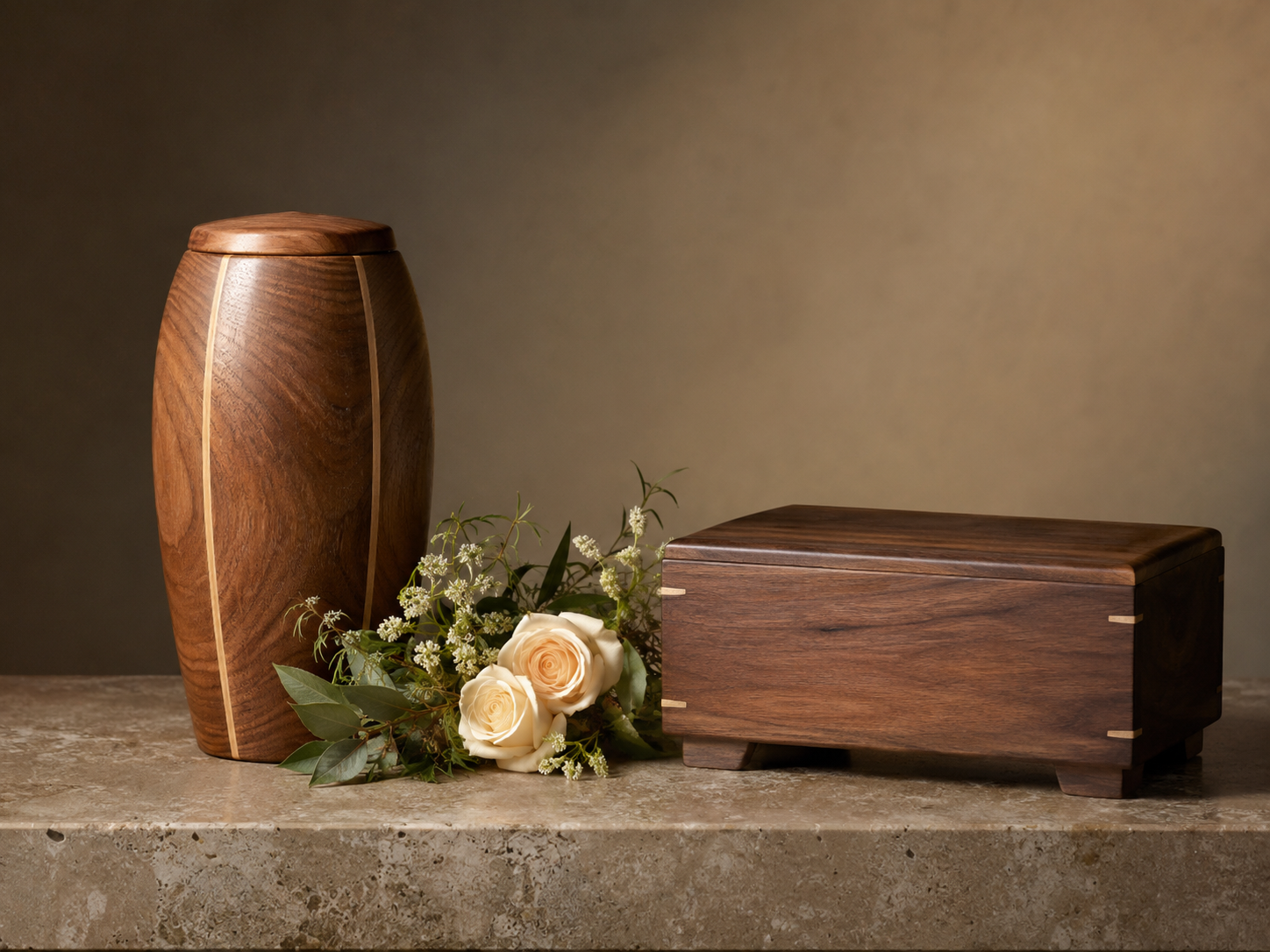 Wooden urn and small coffin with flowers on a stone surface