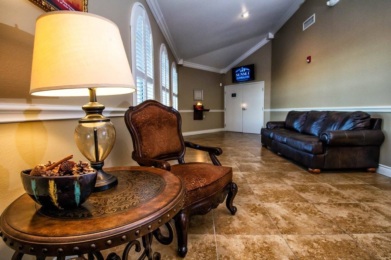 Elegant waiting room with leather sofa, ornate chairs, lamp, and polished marble floor