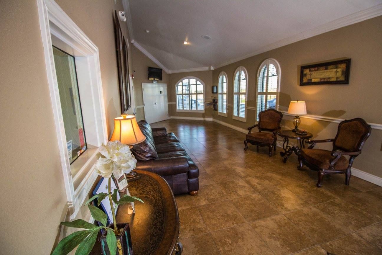 Spacious beige hallway with arched windows, leather chairs, lamps, and polished tile flooring