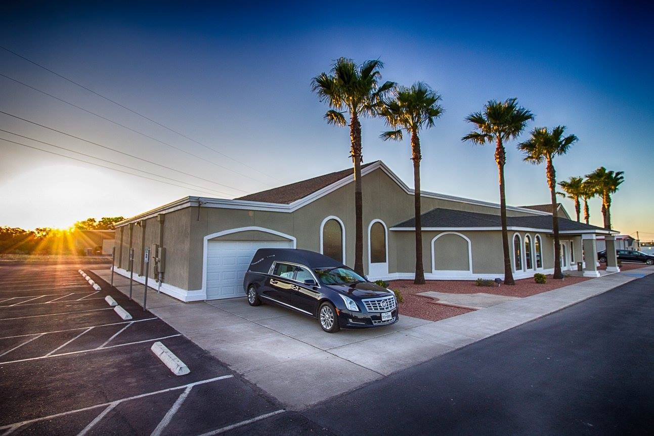 Sunset view of a house with palm trees and a black SUV parked in the driveway