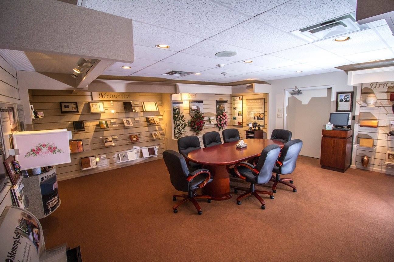 Conference room with a large oval table, rolling chairs, and display shelves under warm lighting.