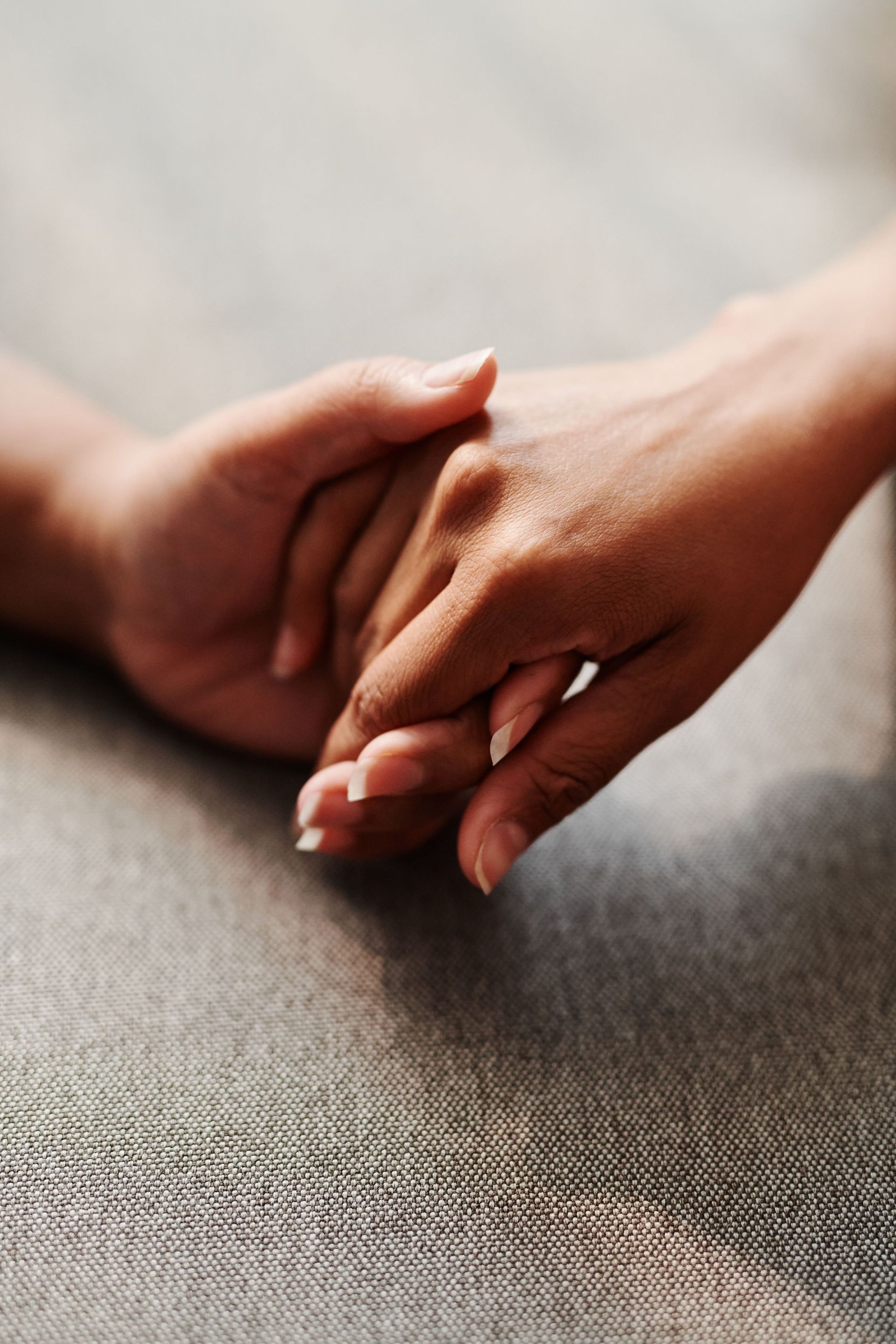 Two hands gently holding on a gray fabric surface