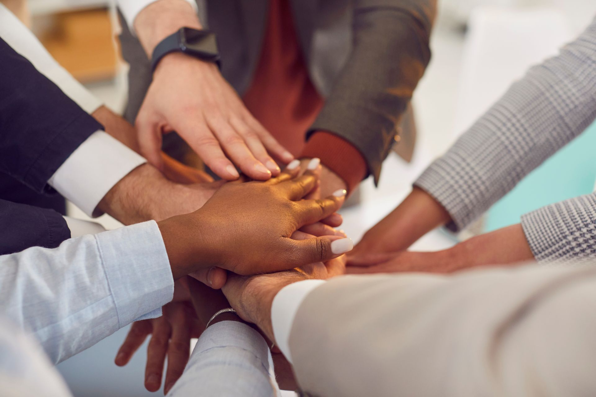 Hands stacked together in a group team huddle indoors
