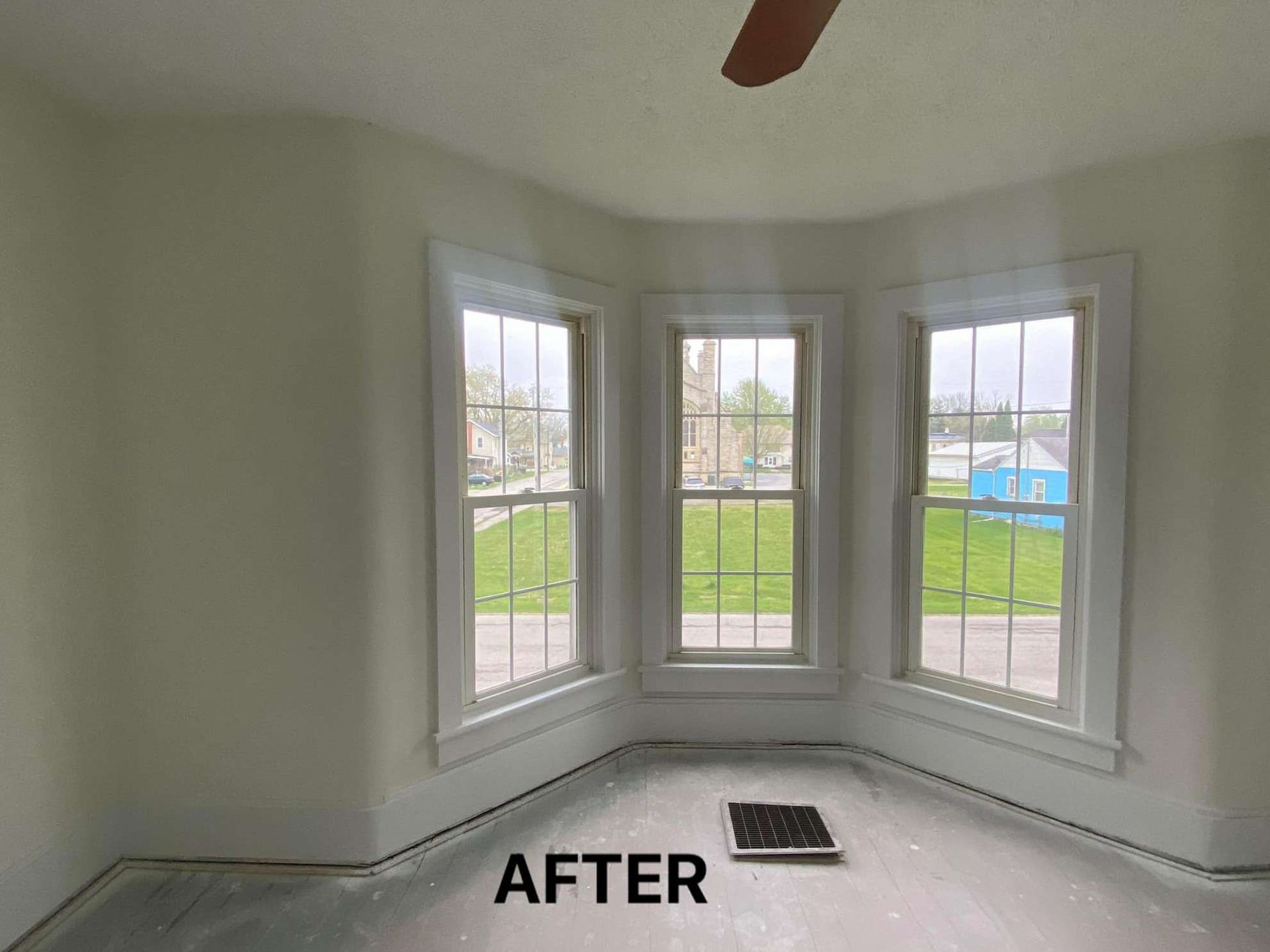 A room with a lot of windows and a ceiling fan.