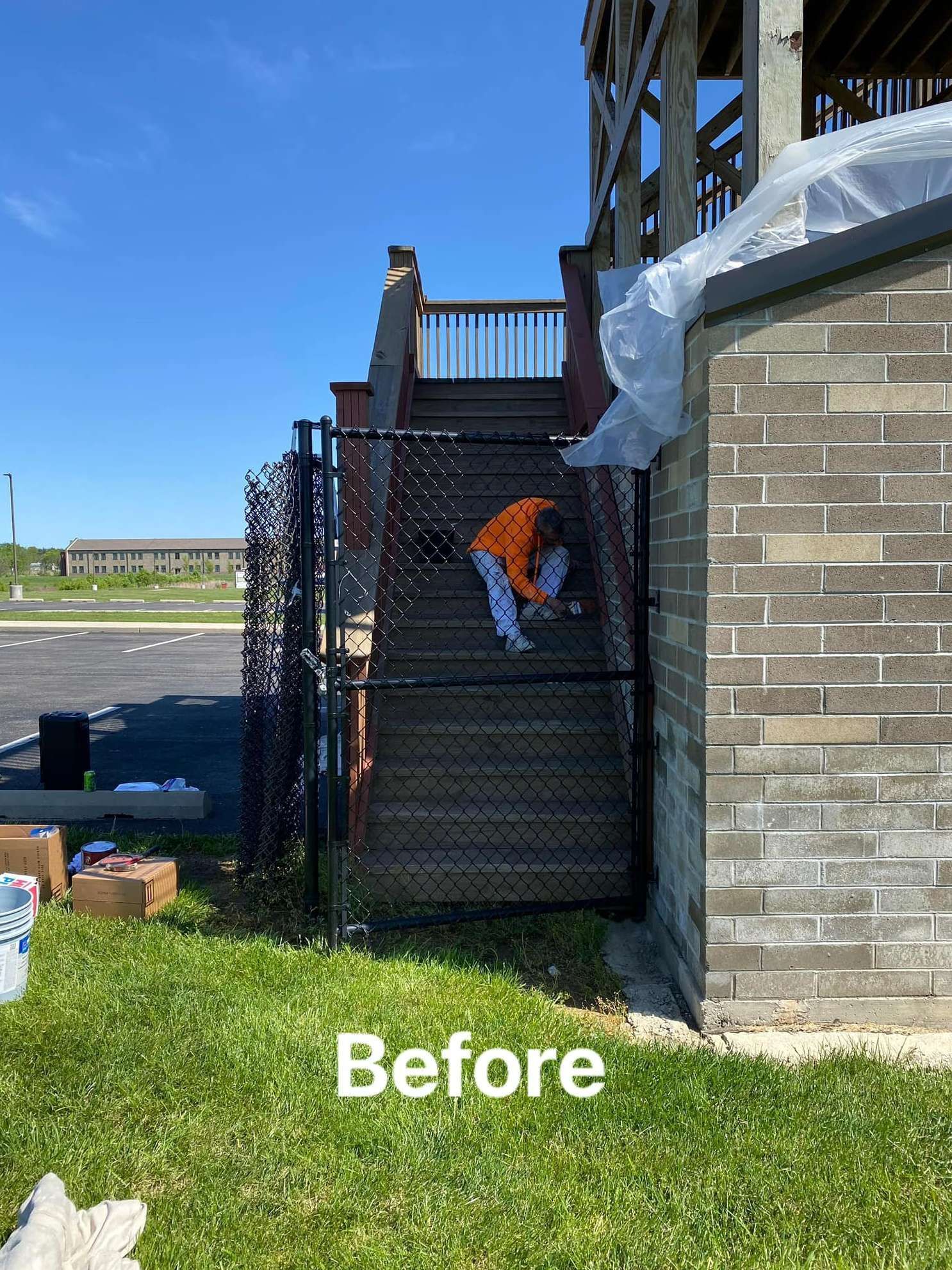 A person is standing on a set of stairs behind a chain link fence.