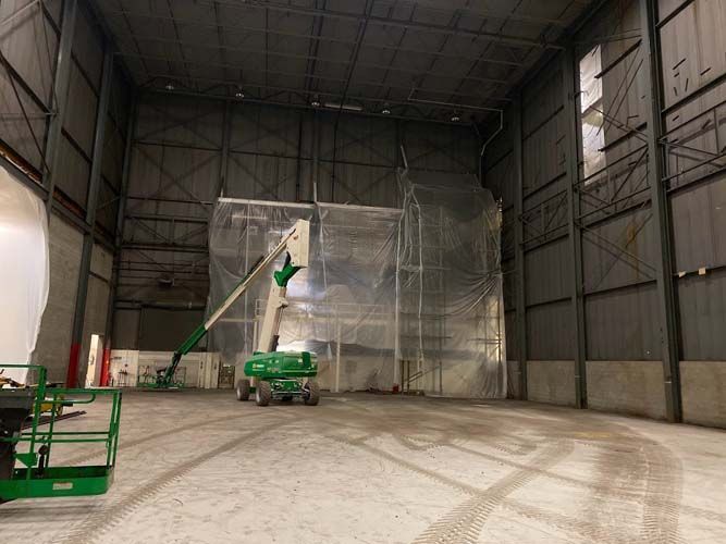 A large warehouse with a green crane in the middle of it.