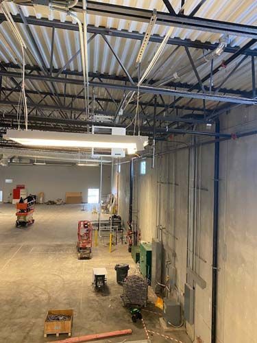A large warehouse with a lot of pipes hanging from the ceiling.