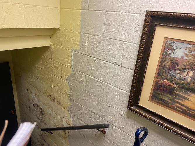 A painting is hanging on a brick wall next to a staircase.