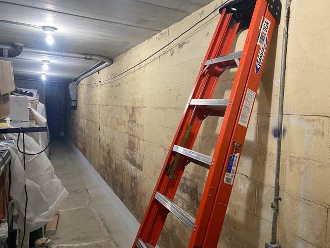 A ladder is leaning against a wall in a dark room.