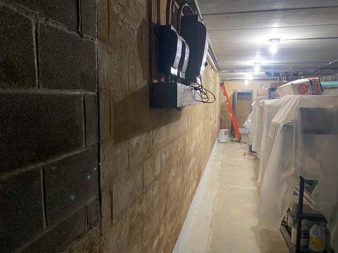 A long hallway in a basement with a brick wall and a ladder.