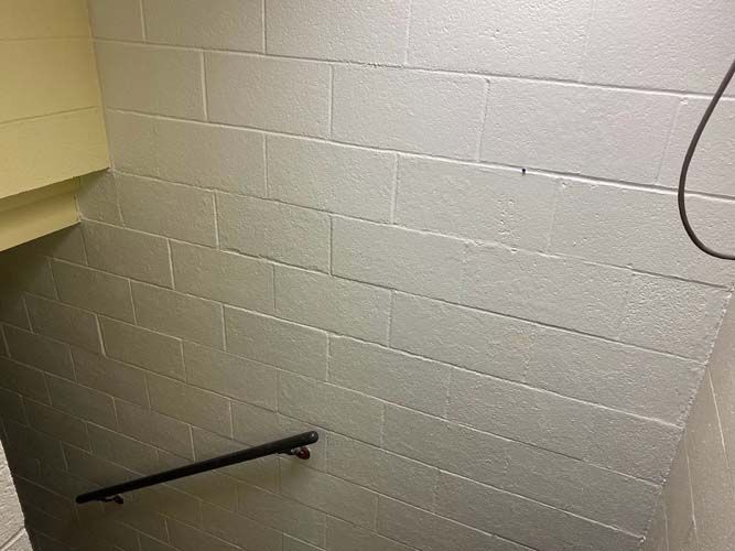 A staircase with a white brick wall and a black railing.