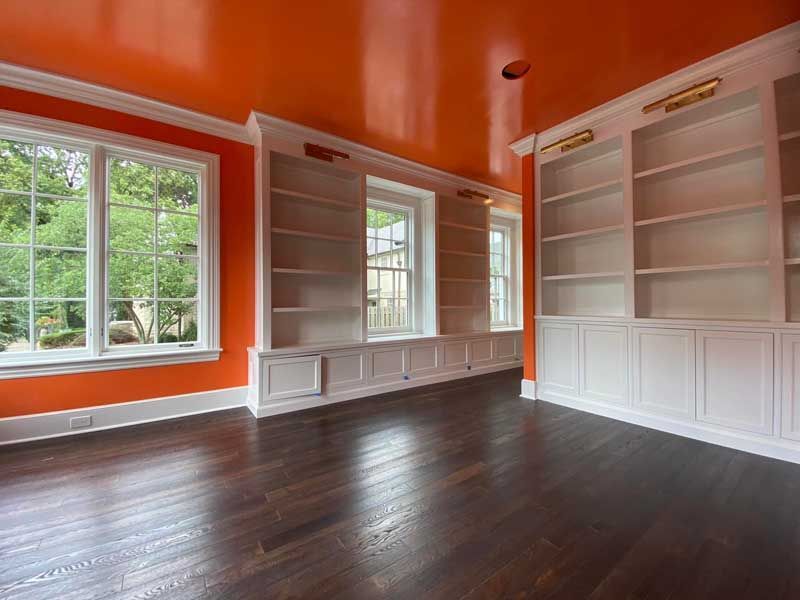 An empty room with orange walls and white shelves