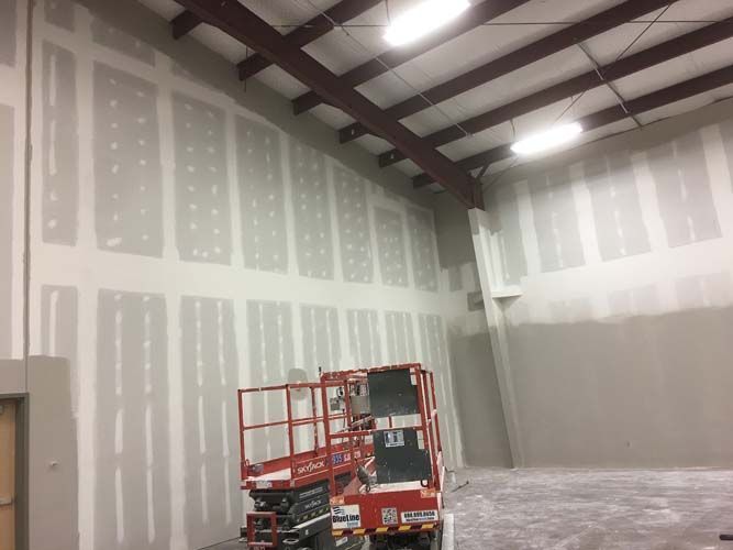 A red and white scissor lift is sitting in a warehouse.