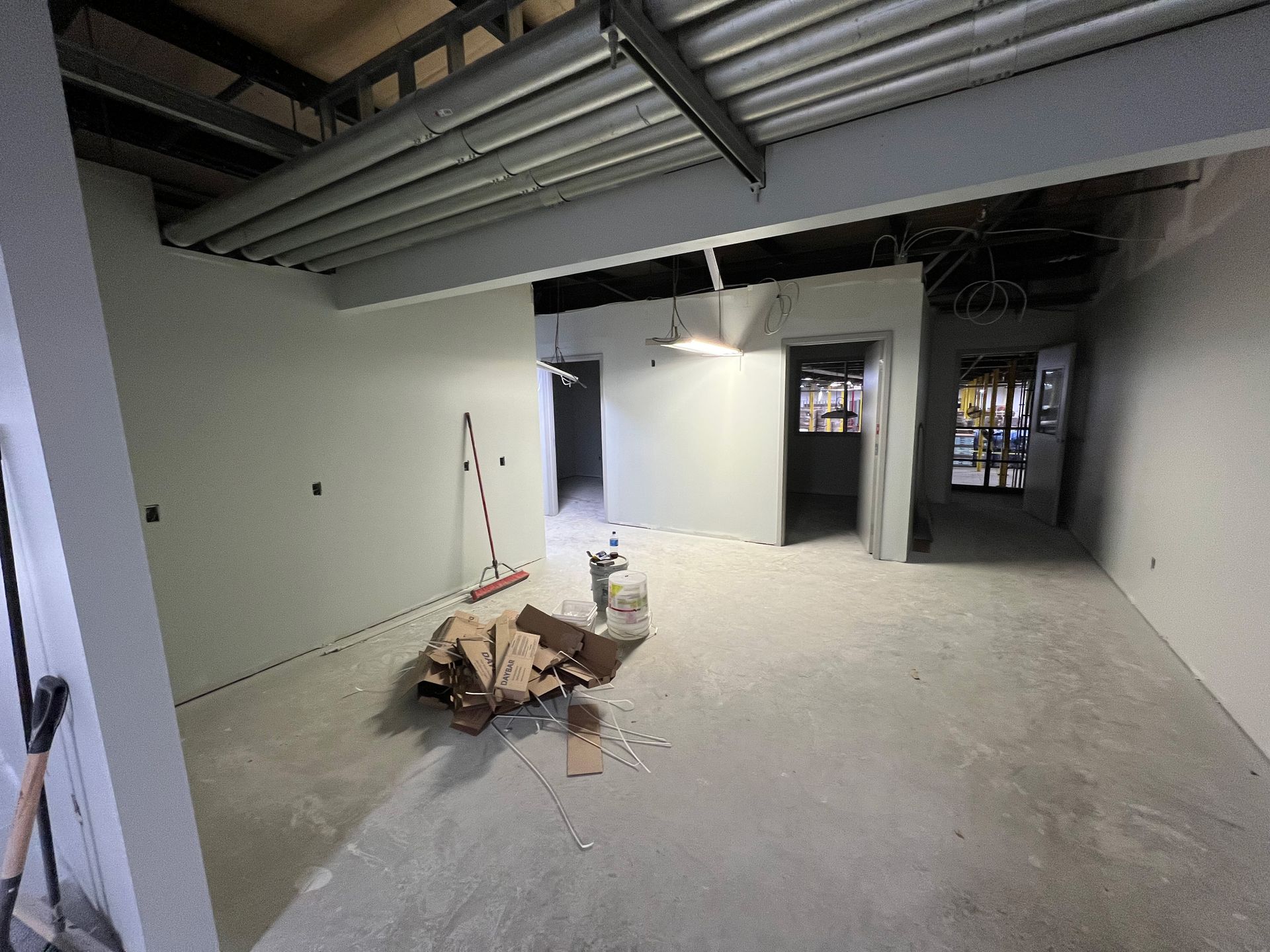 An empty room with white walls and a broom on the floor.
