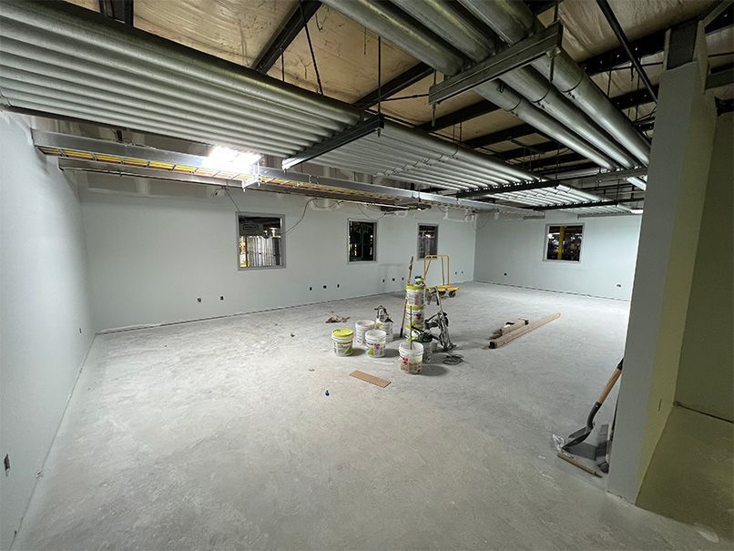 A large empty room with a lot of pipes hanging from the ceiling.