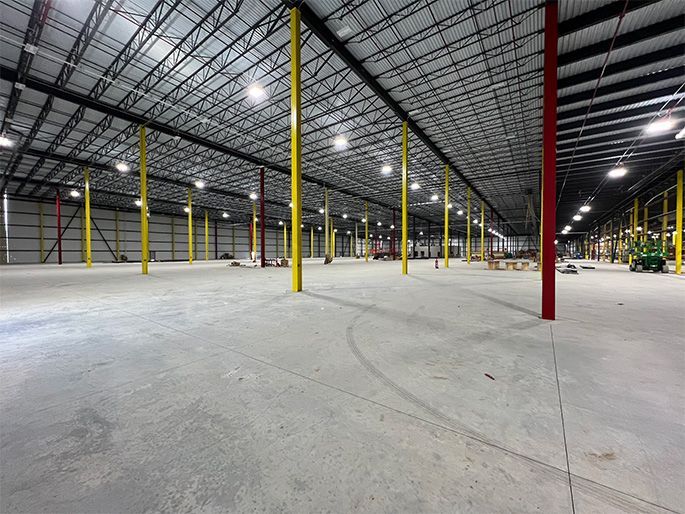 An empty warehouse with yellow poles and a concrete floor