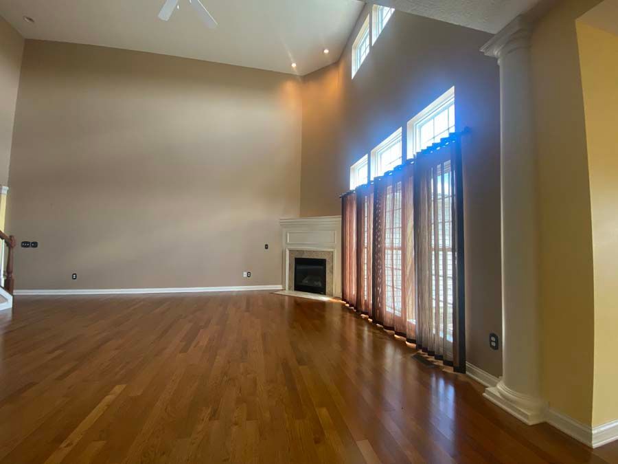 An empty living room with hardwood floors and a fireplace.