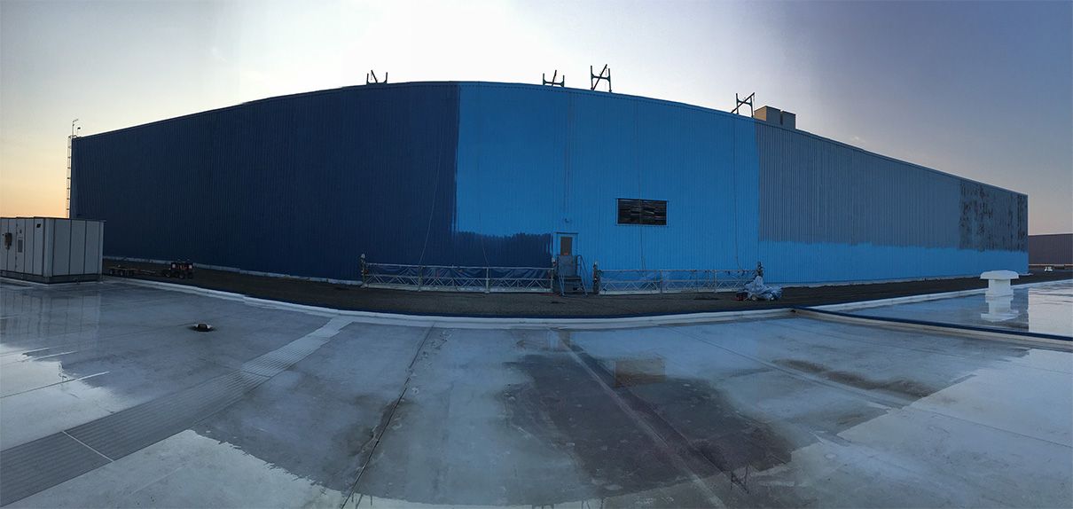 A large blue building is sitting on top of a concrete roof.