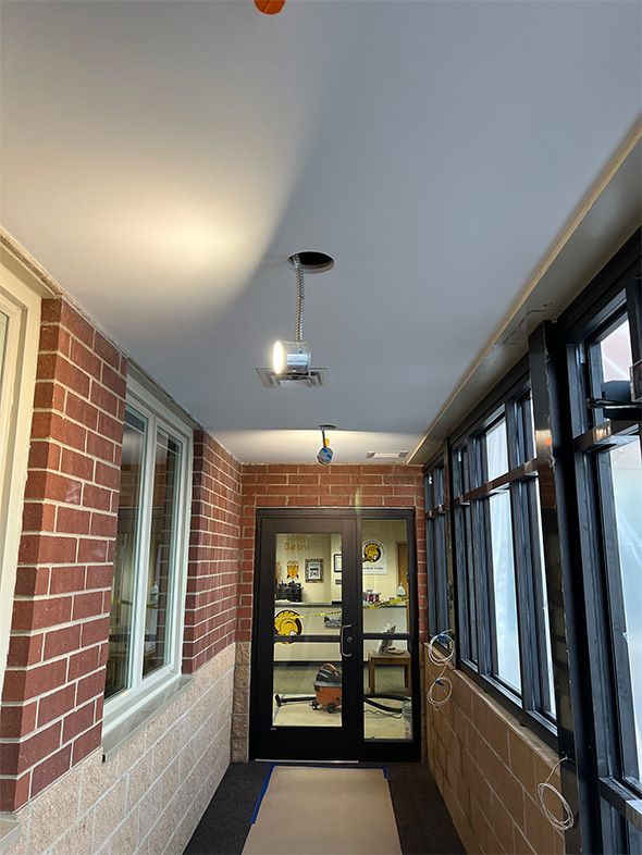 A long hallway with a brick wall and a glass door