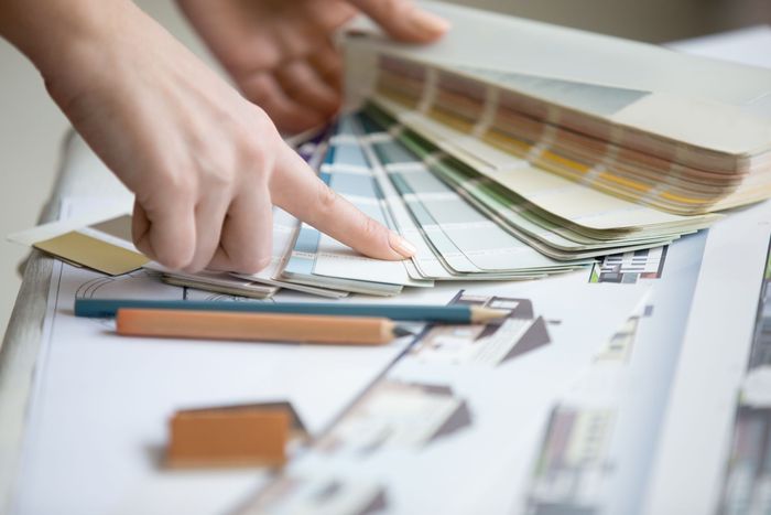 A person is pointing at a color swatch on a table.