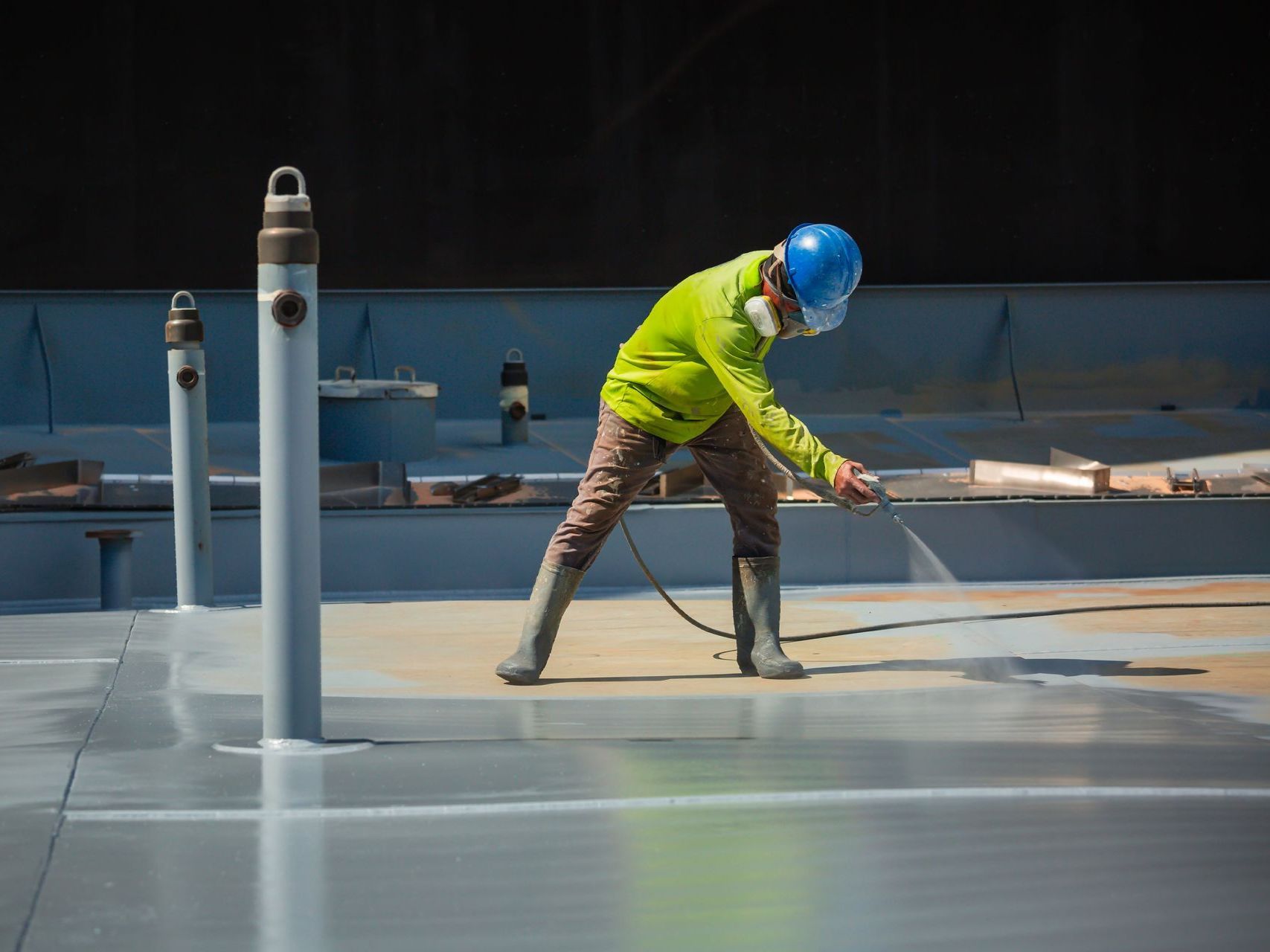 A man is spraying paint on a concrete surface.