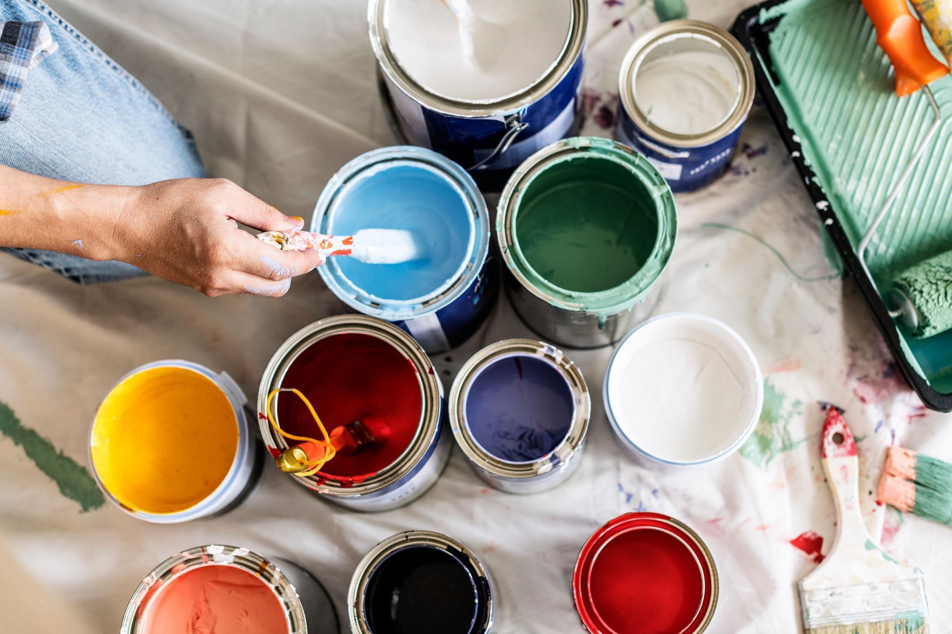 A person is mixing paint in a can with a brush.