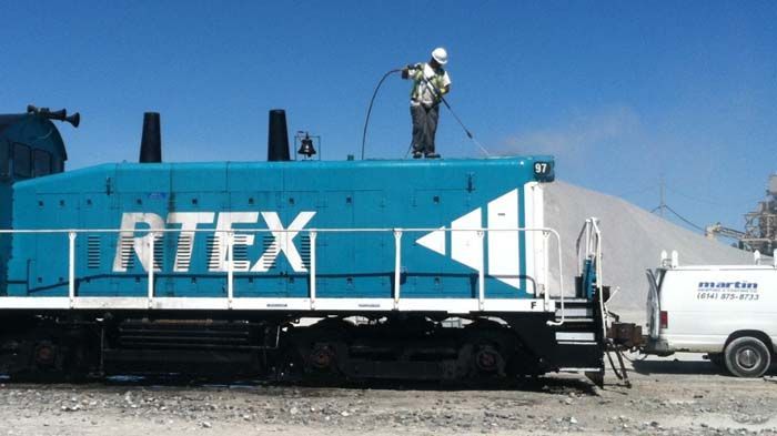 A man is standing on top of a train that says rtex