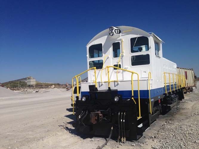 A blue and white train is parked in the dirt