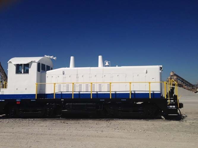 A blue and white train is parked in a dirt field