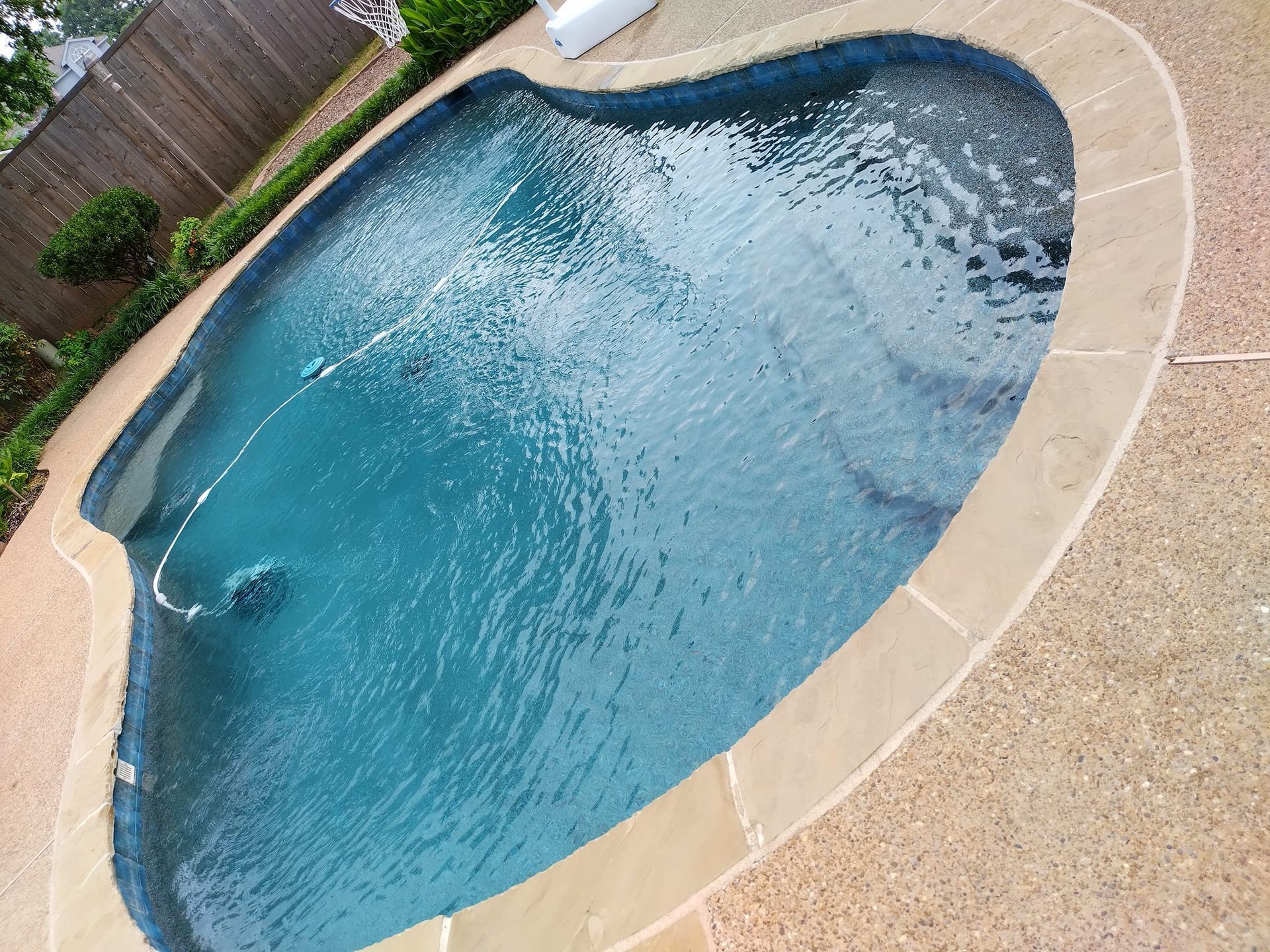 Swimming pool with blue water and tan border.