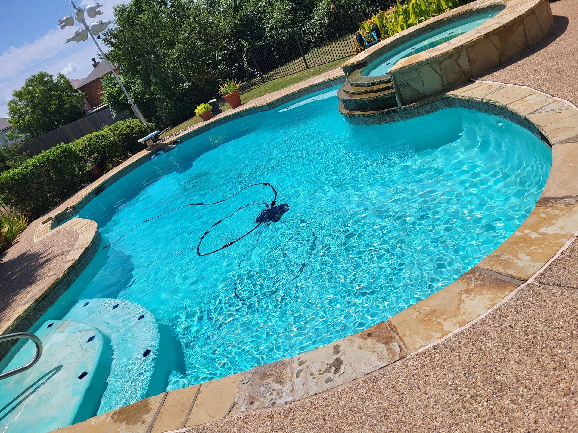Pool with clear blue water and attached hot tub on a sunny day.