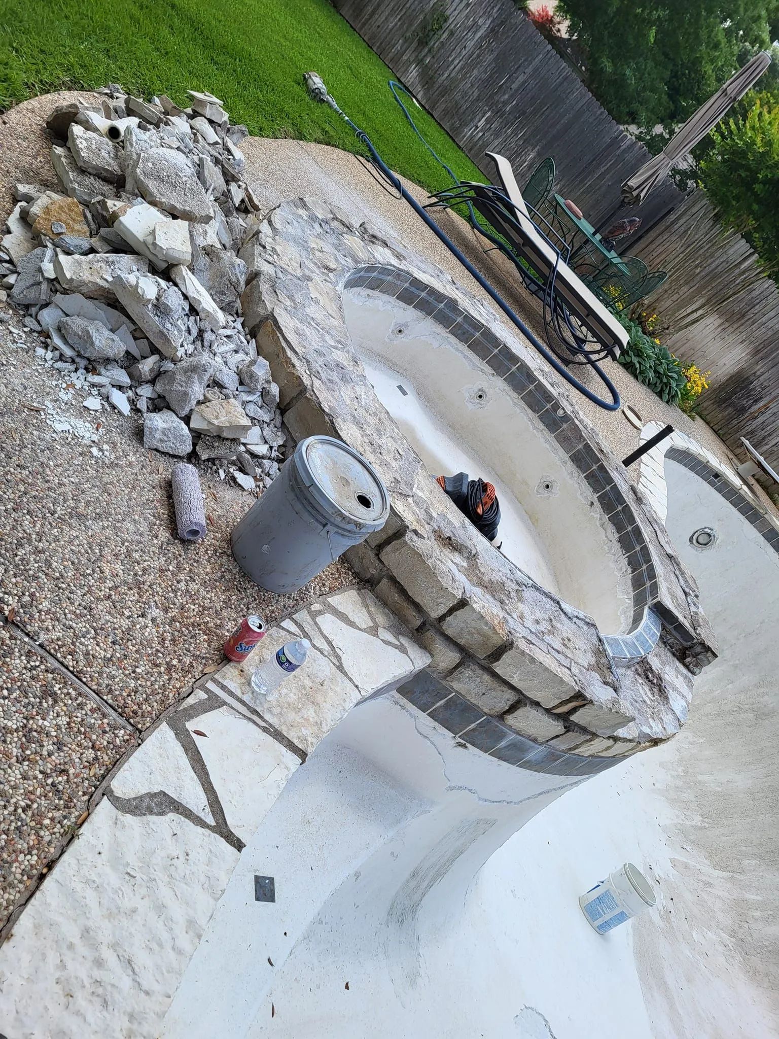 Backyard with a stone fire pit and curved concrete seating area beside a swimming pool