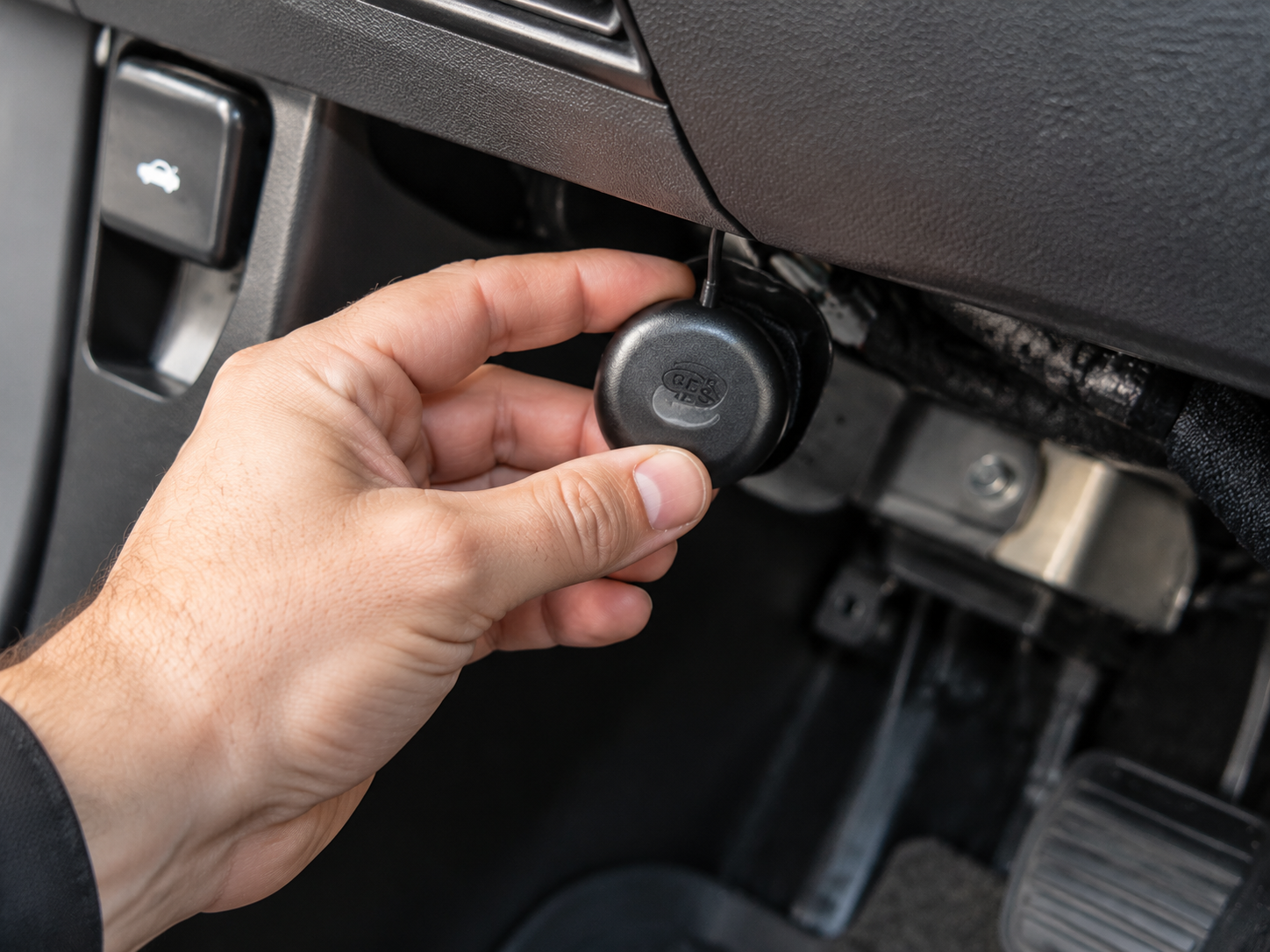 Hand adjusting a car’s under-dash control knob near the pedals