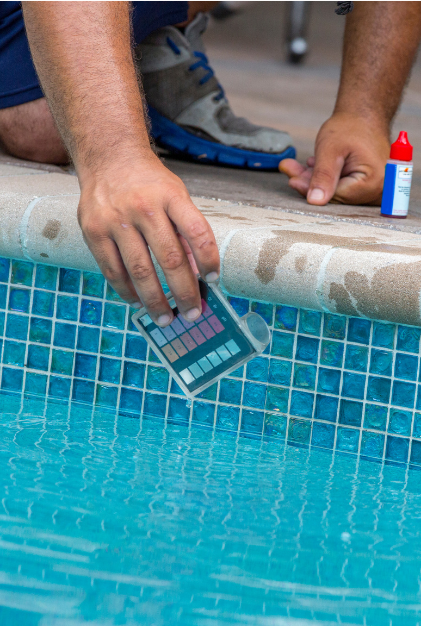 A picture of someone reaching down in a pool with a water tester.