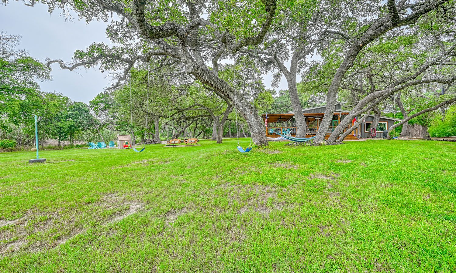 A large lush green field with trees and a house in the background.