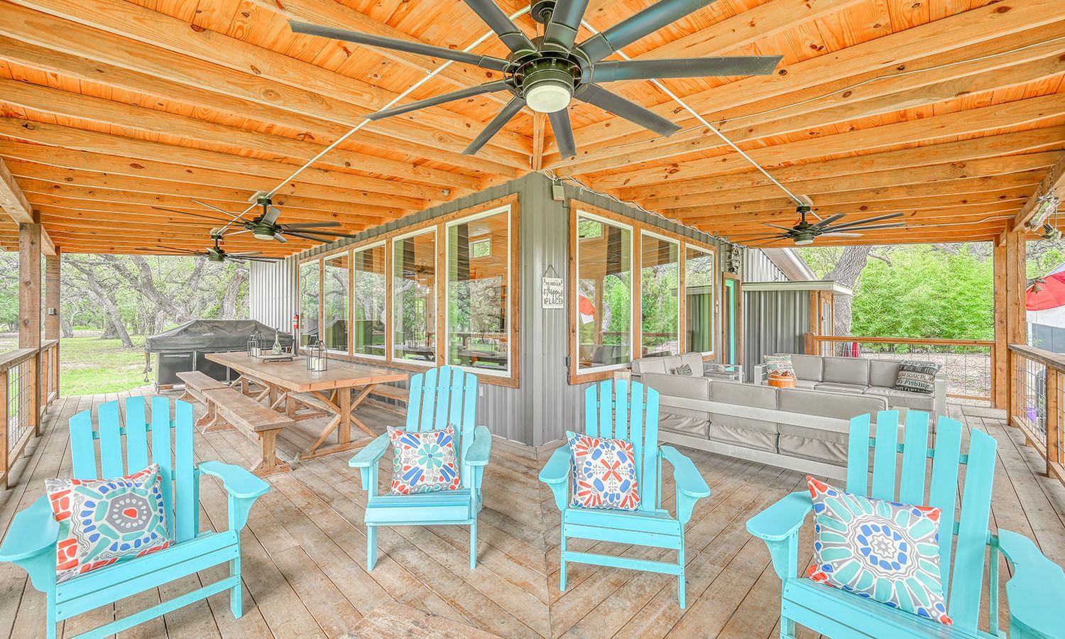 A screened in porch with blue chairs and a ceiling fan.