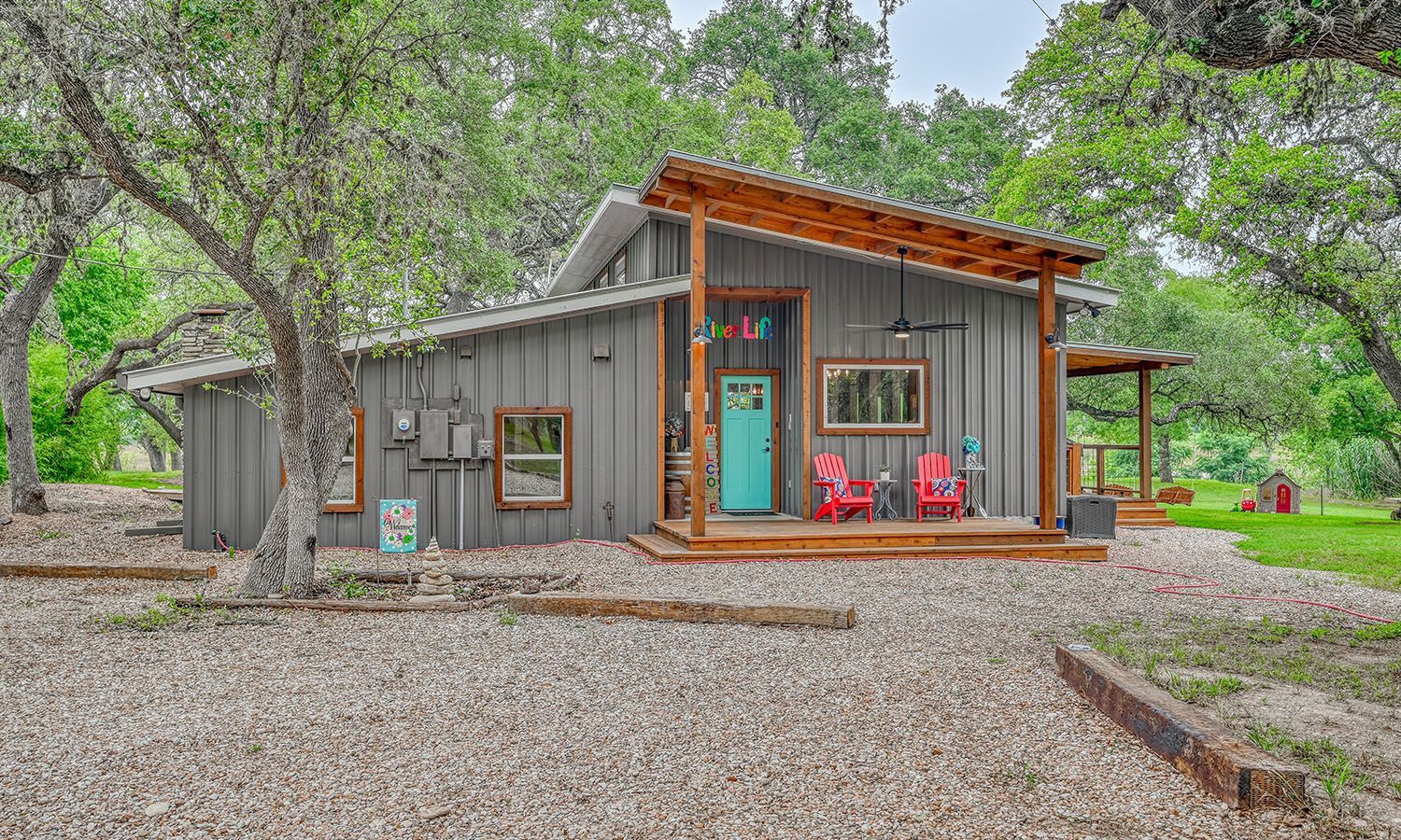 A small house with a blue door and red chairs on the porch.