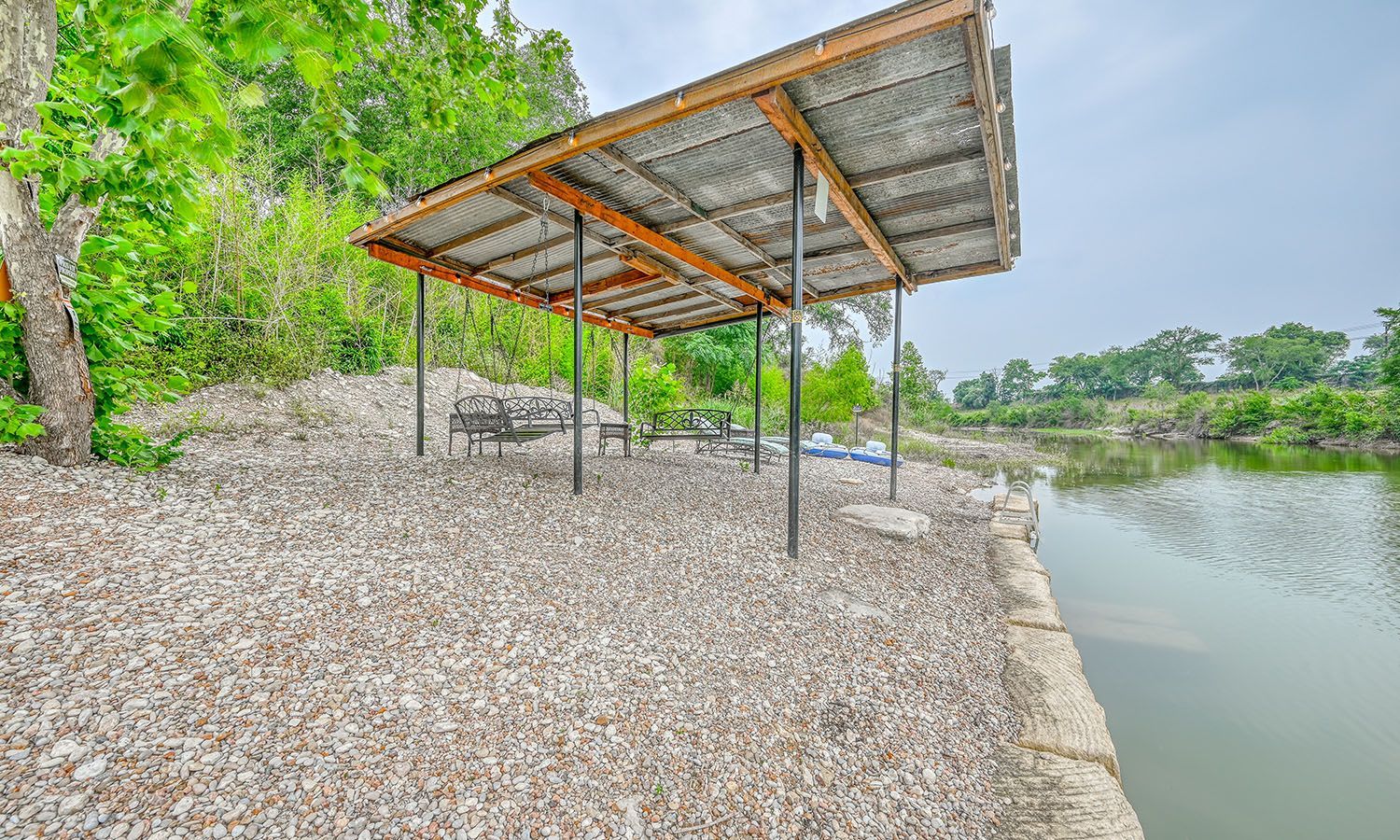 A covered area next to a lake with a wooden structure.