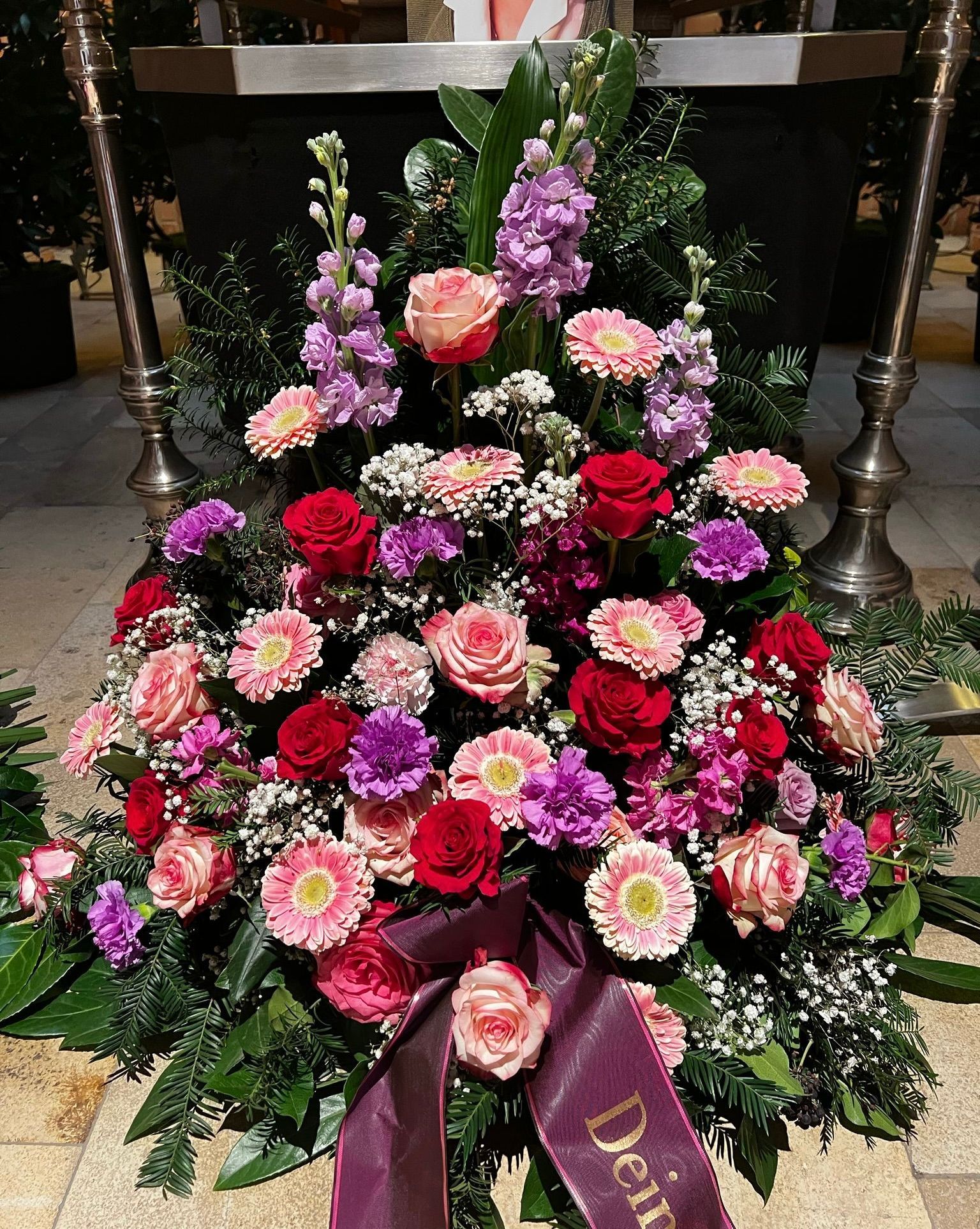 Ein Gesteck aus rosa, roten und violetten Blüten. Dazwischen weißes Schleierkraut.