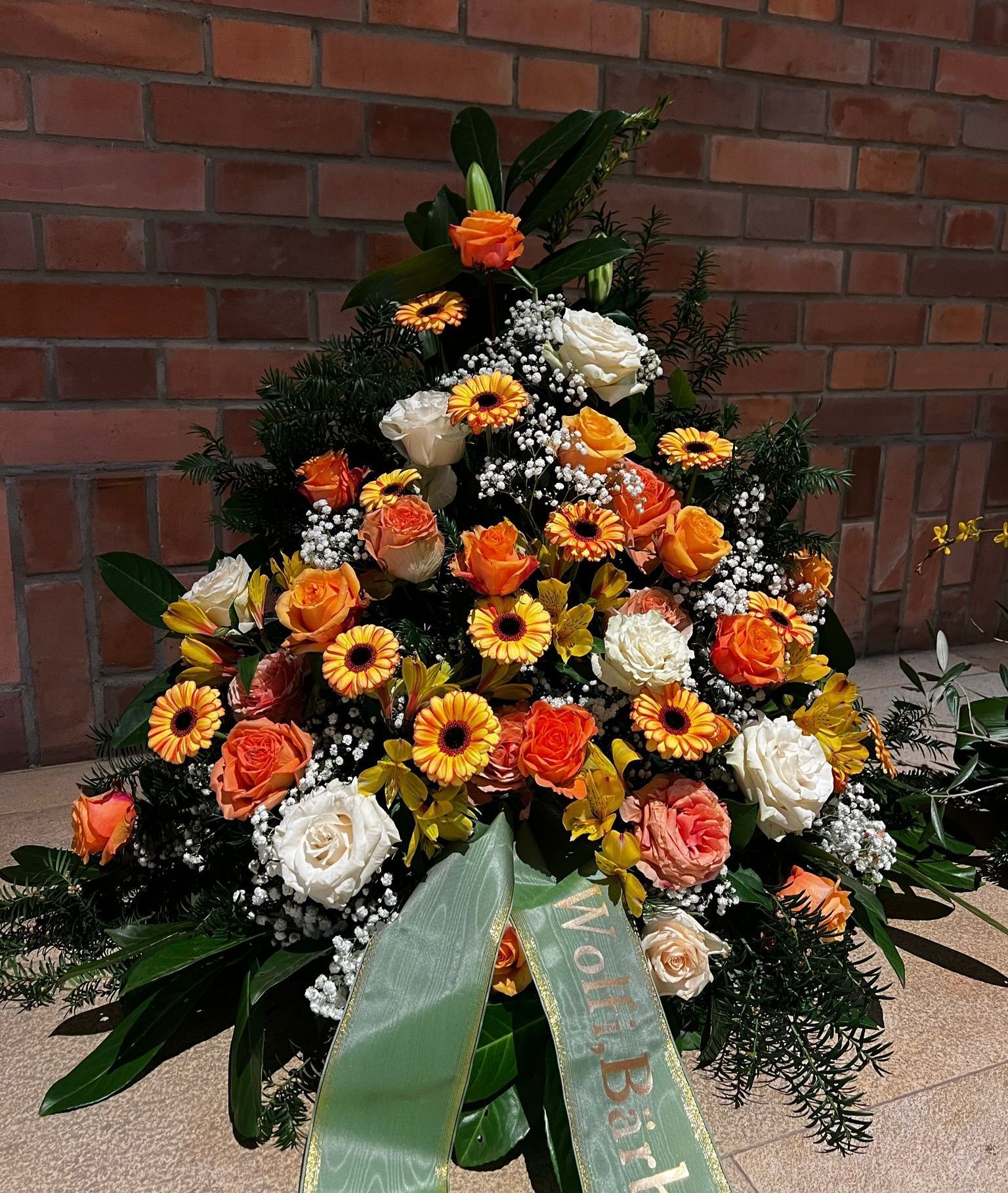Ein Gesteck aus gelben, orangen und weißen Blüten. Dazwischen Schleierkraut.