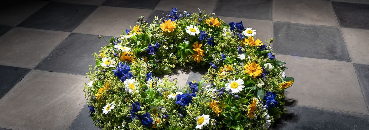 Auf einem karierten Boden liegt ein Blumenkranz.