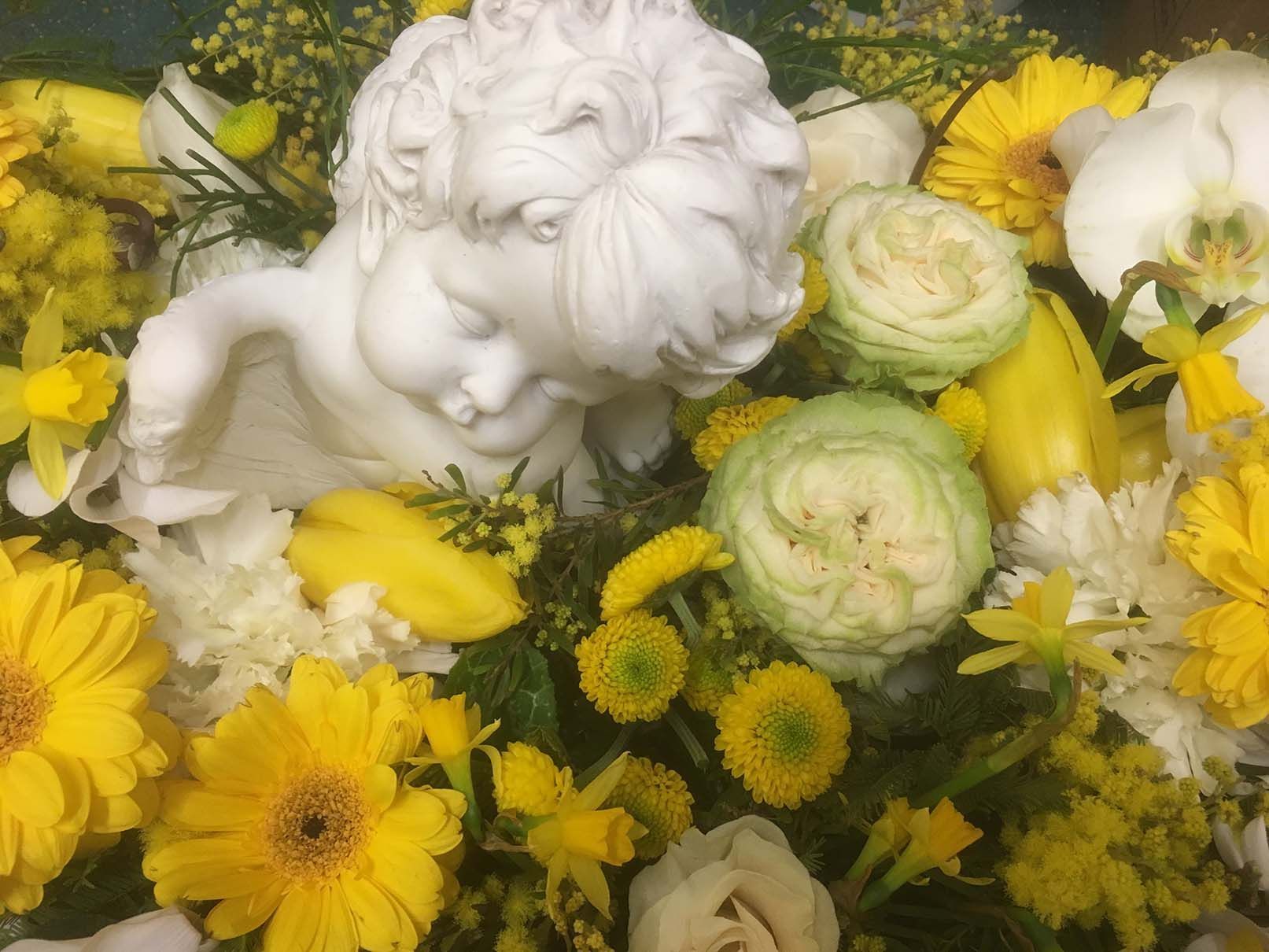 Eine Statue eines Engels ist von gelben und weißen Blumen umgeben
