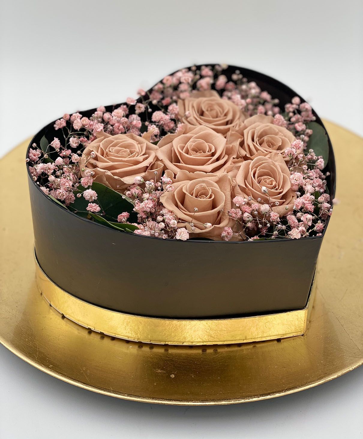 Eine herzförmige Schachtel gefüllt mit rosa Rosen und Schleierkraut