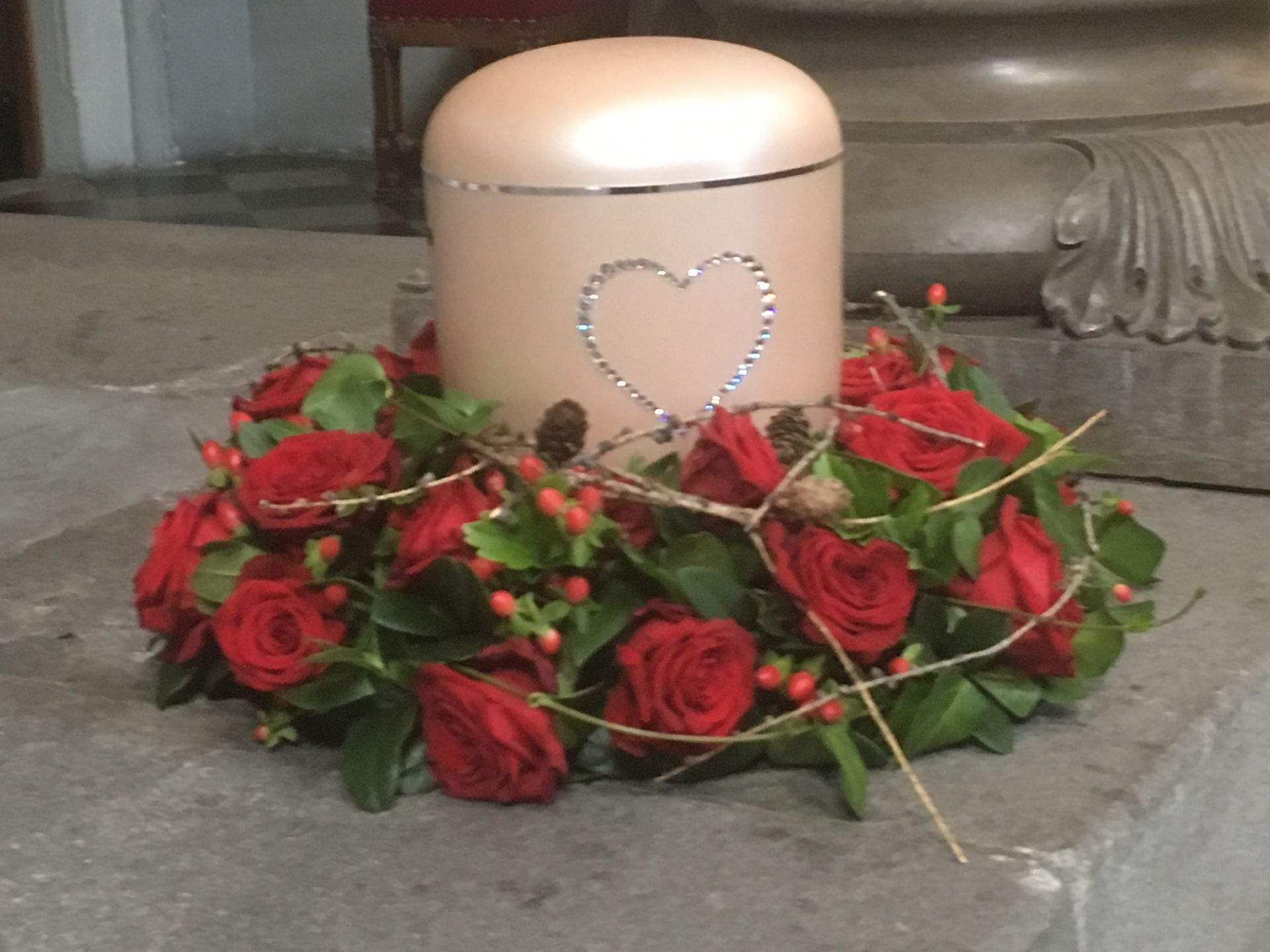 Eine Urne mit einem Herzen darauf ist von roten Rosen umgeben